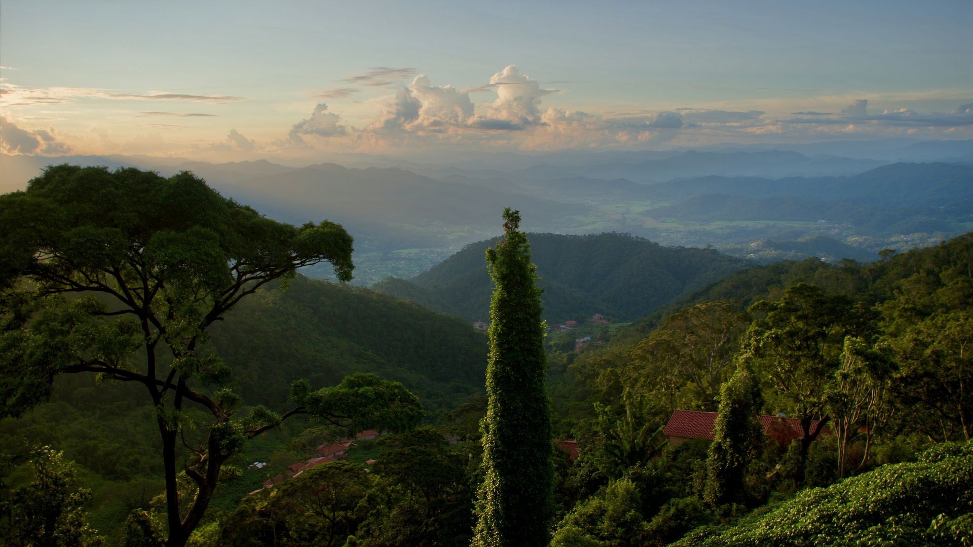 Sunset over Costa Rica's Central Valley: layered mountains, deep green in the foreground and tile roofs below