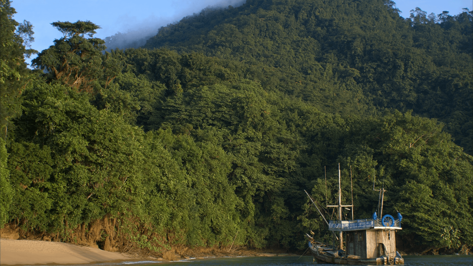 Bote de pesca anclado en una caleta de Quepos, con la selva bajando hasta el agua