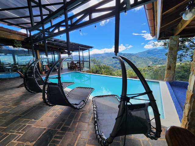 Terraza junto a la piscina infinita con camastros colgantes y vista a las montañas de Aserrí